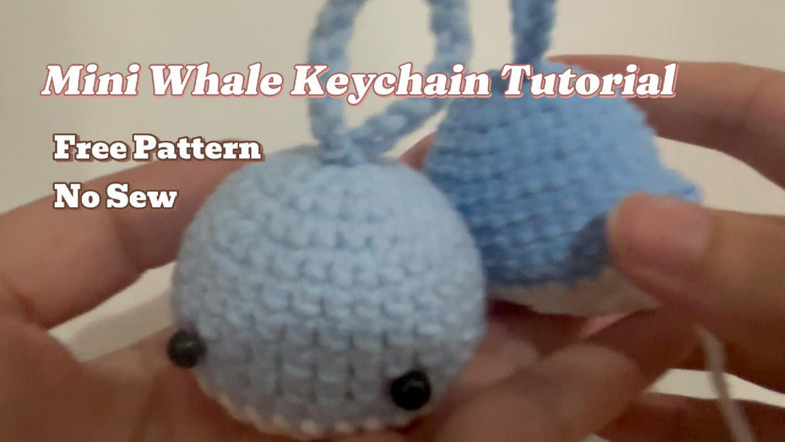 Crochet mini whale keychain in light blue chenille yarn held in hand