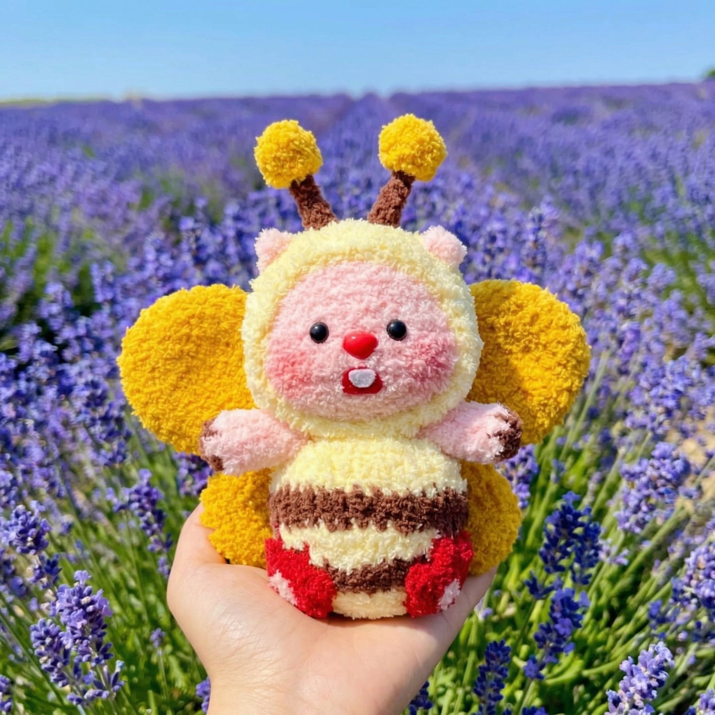 Chubby bumble bee amigurumi held in hand, made with soft plush yarn in yellow, orange and pink